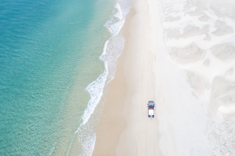 Aerial view of a 4WD driving along the beach on K'gari Island, Queensland © Tourism and Events Queensland